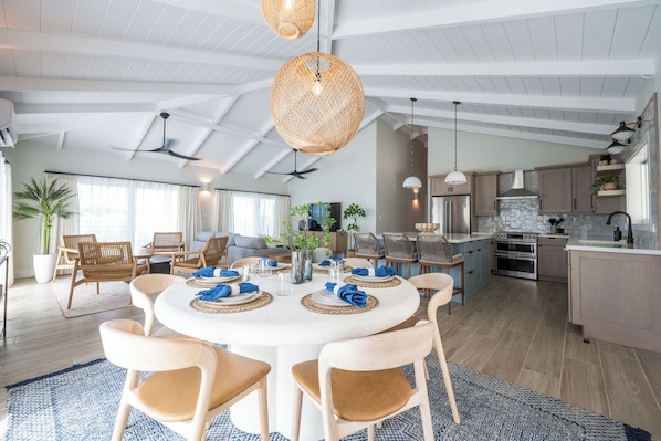 A spacious living area with a round dining table, wicker chairs, and a kitchen with modern appliances. - Villa Cabrita - Walk to the Ritz beach! East End (St. Thomas)