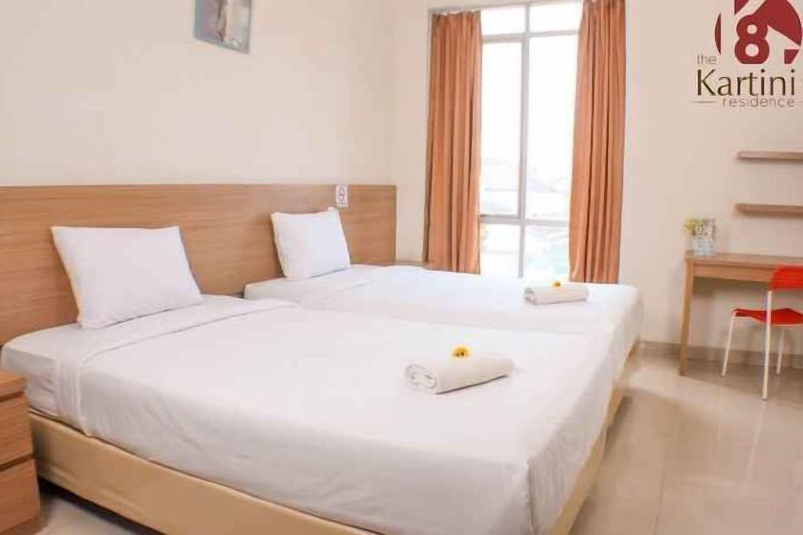 Een hotelkamer met twee bedden, een bureau en een stoel.