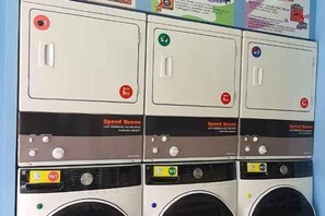 A row of four stacked laundry machines with control panels and a speed dial. - The Kartini 8 Residence - Mangga Besar (Central Jakarta)