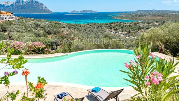 A pool with a view of a mountainous coastline.