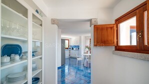 A kitchen with white cabinets, a blue tiled floor, and a wooden door.