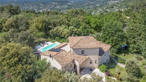 A villa with a swimming pool, surrounded by lush greenery and hills.