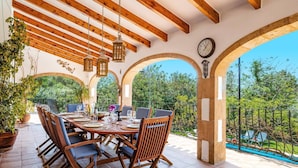 An outdoor dining area with a wooden table and chairs, surrounded by arches and potted plants. - Villa Jacqueline by Villa Plus (Montgo de Toscamar)