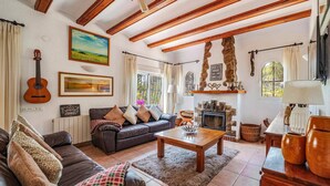 A cozy living room with a fireplace, a sofa, a coffee table, and a guitar. - Villa Jacqueline by Villa Plus (Montgo de Toscamar)