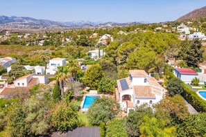 Residential homes blend seamlessly into lush surroundings, surrounded by gardens, pools, and majestic mountains.