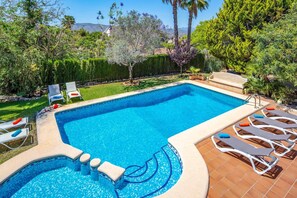 Relax by the pool surrounded by lush greenery and comfortable lounge chairs.