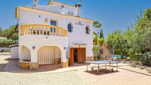 A white building with a balcony, a door, and a small table. - Villa Jacqueline by Villa Plus (Montgo de Toscamar)