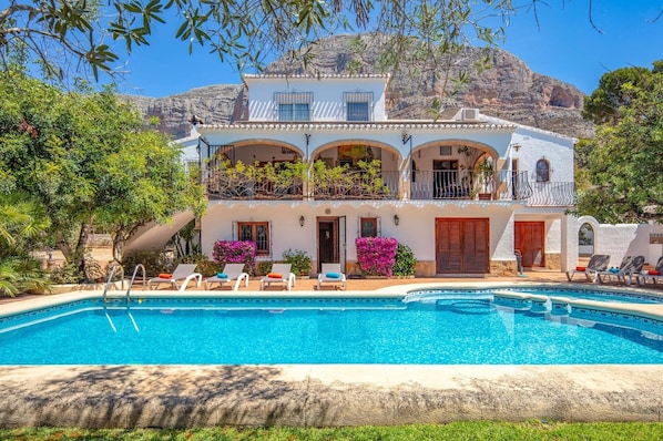 Relax by the pool surrounded by lush greenery and scenic views of the surrounding hills.