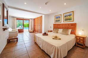 Relax in a spacious room with a large bed, comfortable seating area, and a window offering a view of the outdoors.