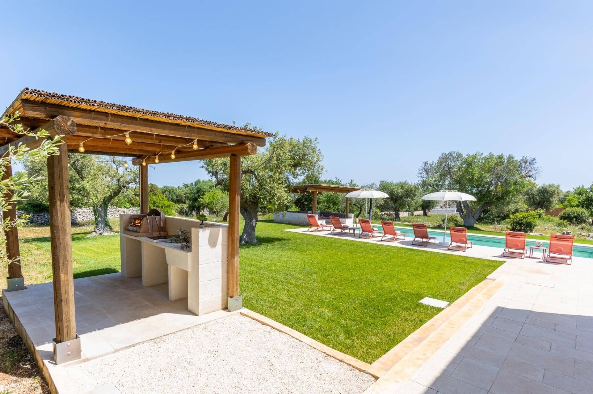 Un patio con barbacoa, mobiliario exterior y piscina.