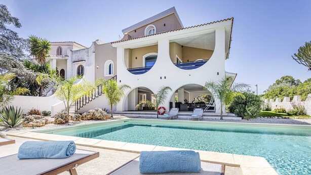 Una villa moderna con piscina, mobiliario exterior y un jardín ajardinado.