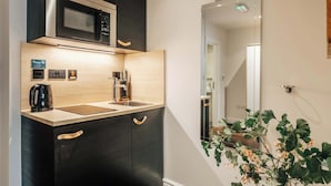 A compact kitchen with a microwave, coffee maker, and a sink.