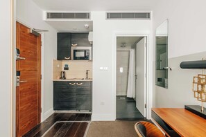 A modern kitchen with a microwave, dark cabinets, and a wooden door.