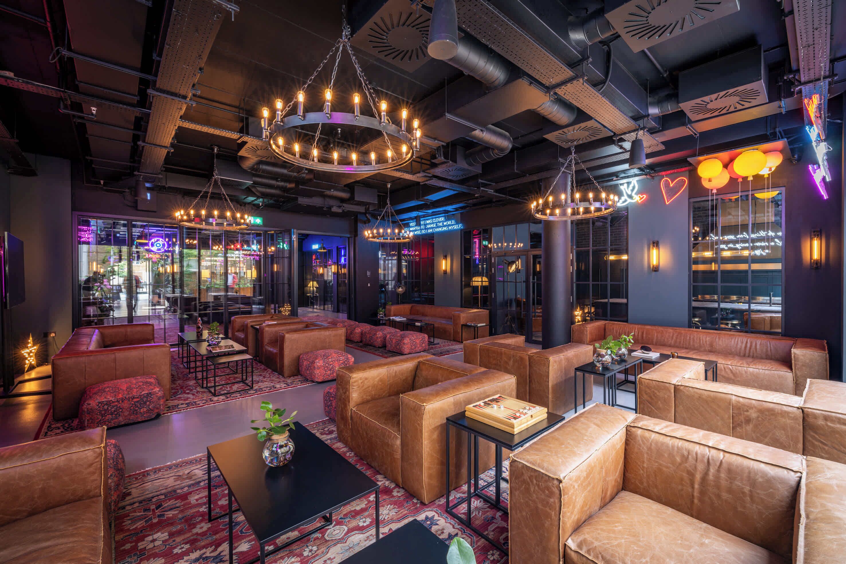 Un espace de détente moderne avec des canapés en cuir, des tables et un éclairage d’ambiance.