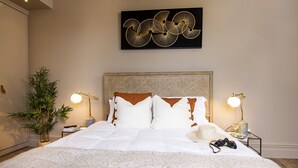Un lit bien fait, avec une literie blanche, une grande tête de lit et un élément décoratif fixé au mur au-dessus.