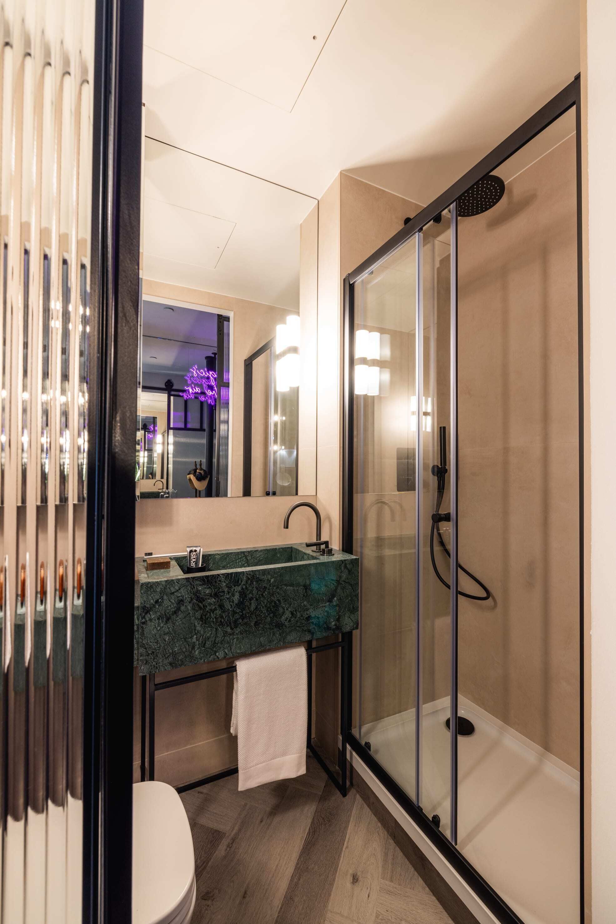 A modern bathroom with a glass shower enclosure, a marble sink, and a toilet.