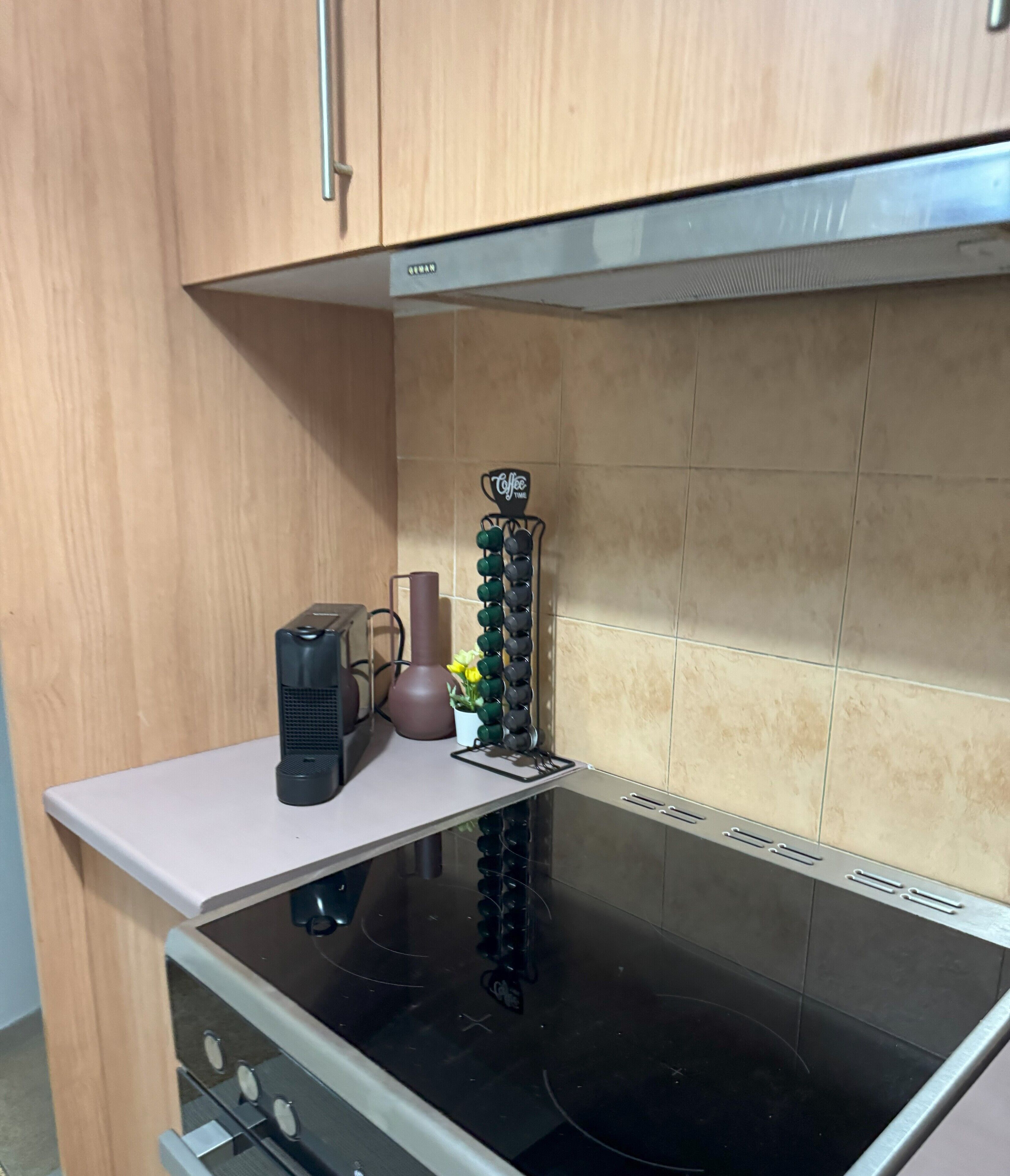 A kitchen with a black stove, a coffee machine, and a mug rack.