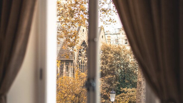A room with a large window, curtains, and a view of a building with a tower. - The Courtfield - Deluxe Studio in Kensington (London)