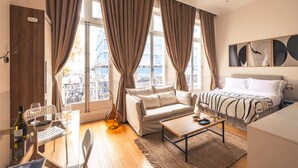 A modern bedroom with a bed, sofa, and dining area. - The Courtfield - Deluxe Studio in Kensington (London)