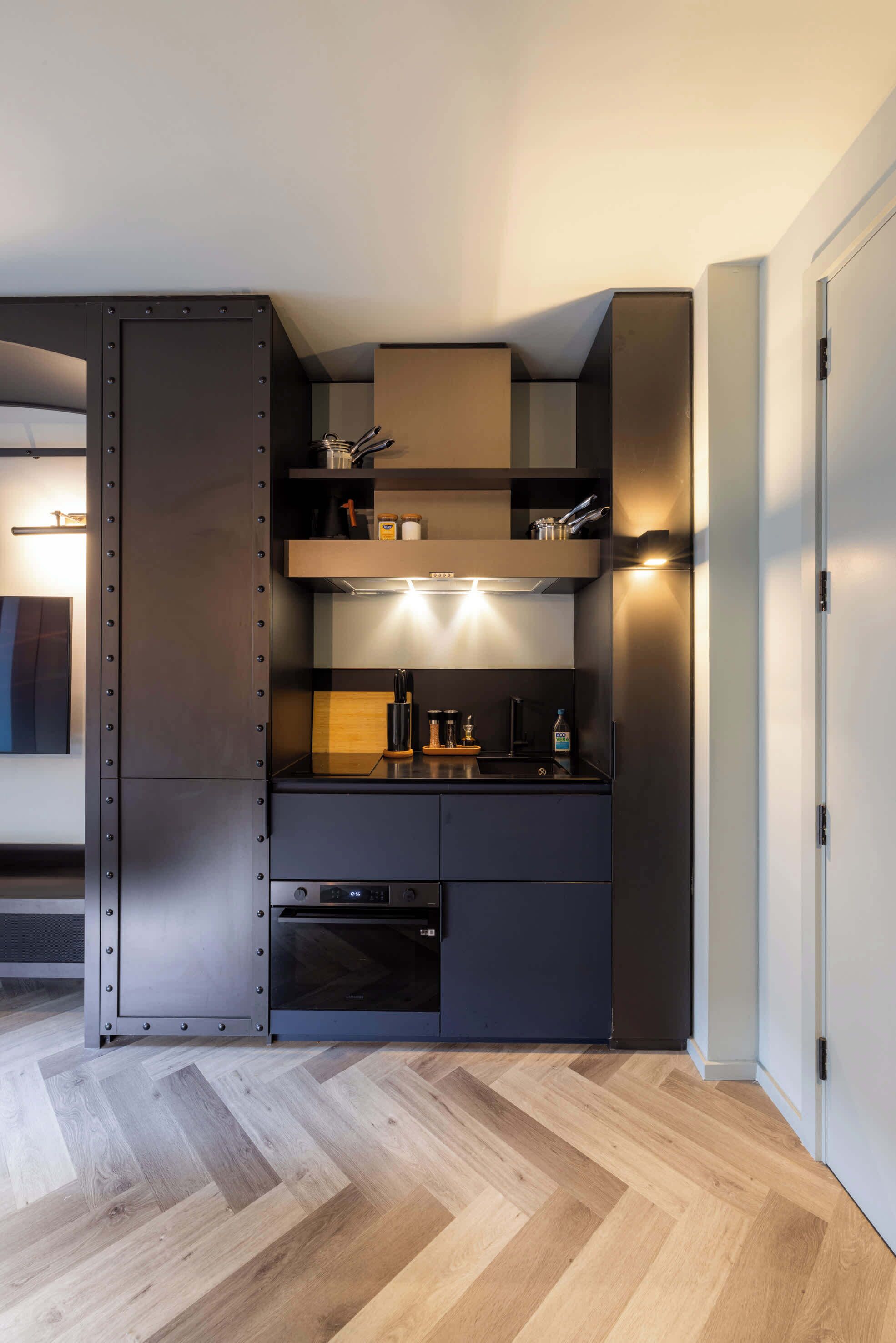 A modern kitchen with built-in appliances, wooden flooring, and a minimalist design.