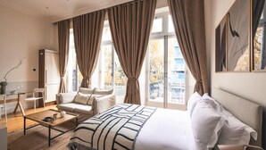 A hotel room with a bed, a sofa, a coffee table, and a desk with a chair.