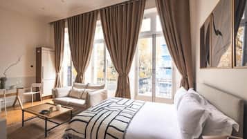 A hotel room with a bed, a sofa, a coffee table, and a desk with a chair.