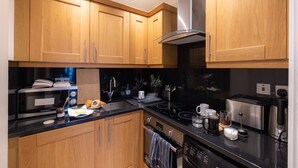 A modern kitchen with wooden cabinets, a stainless steel range hood, and various appliances including a microwave, toaster, and coffee maker.