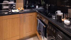 A modern kitchen with wooden cabinets, a black countertop, stainless steel appliances, and a dishwasher.