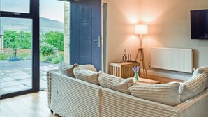 Una sala de estar moderna con un sofá, una lámpara y vistas a través de un ventanal.