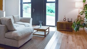 Una sala de estar con un sofá, una mesa de centro y una mesita auxiliar de madera con una lámpara.