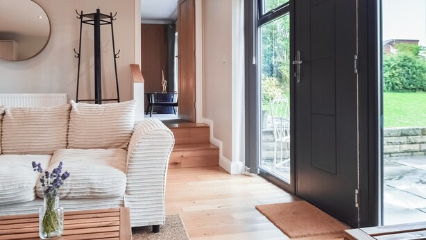 Una sala de estar moderna con un sofá, una mesa de centro y un jarrón de flores. Hay un ventanal con vistas al exterior.