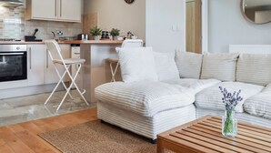 Una sala de estar moderna con un sofá, una mesa de centro y una zona de cocina con armarios y una estufa.