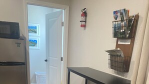 A kitchen with a stainless steel refrigerator, wooden stools, a black table, and a fire extinguisher on the wall. - Cheerful cabin with KING bed and WiFi, AC in charming Plainview (Plainview)