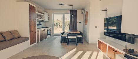 Una sala moderna con sofá, mesa de comedor y televisor.