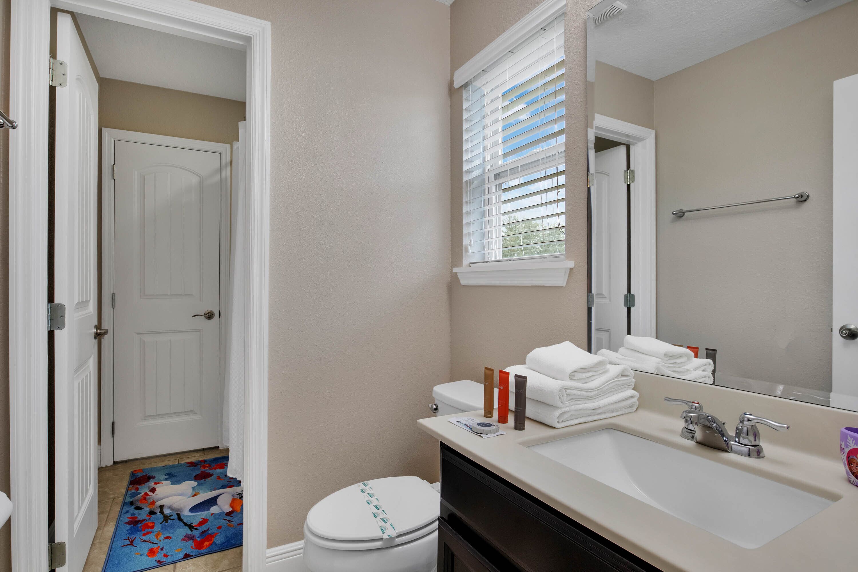 A bathroom with a toilet, sink, and window with blinds.