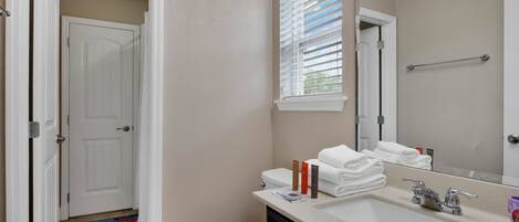 A bathroom with a toilet, sink, and window with blinds.