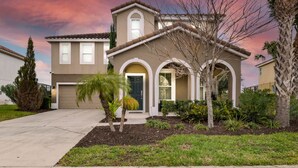 A two-story house with a garage, a front porch with a small tree, and a well-maintained lawn. - Last Minute Disney! Private Pool, Hot Tub & Themed Bedrooms. Book Now! #65531 (Orlando)