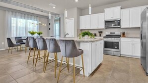A modern kitchen with white cabinets, stainless steel appliances, and a central island with bar stools.