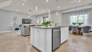 A modern kitchen with a central island, white cabinetry, and pendant lighting.