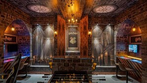 Una habitación con mesa de fútbol, paredes de ladrillo y un letrero con temática de Harry Potter.