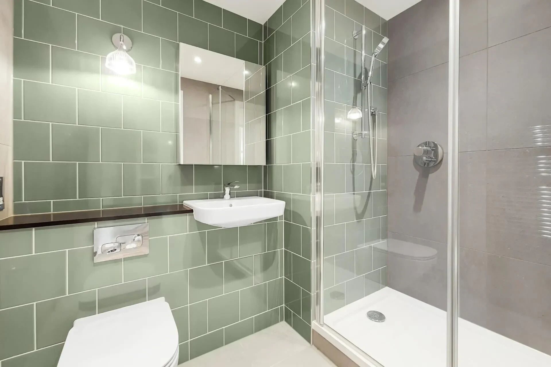 A modern bathroom with a glass-enclosed shower, a white sink, and a toilet.
