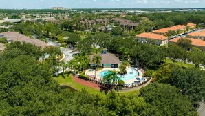 An aerial view of a residential area with a central swimming pool surrounded by houses and greenery. - Last Minute Disney Getaway! Townhouse with Private Pool. Book Now! #65649 (Orlando)