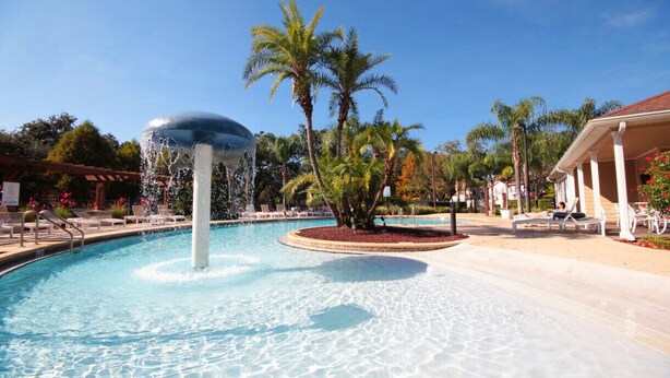A swimming pool with a water fountain, palm trees, and lounge chairs. - Last Minute Disney Getaway! Townhouse with Private Pool. Book Now! #65649 (Orlando)