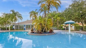 A swimming pool surrounded by palm trees and a building with a glass facade. - Last Minute Disney Getaway! Private Pool & Themed Bedrooms. Book Now! #65673 (Orlando)