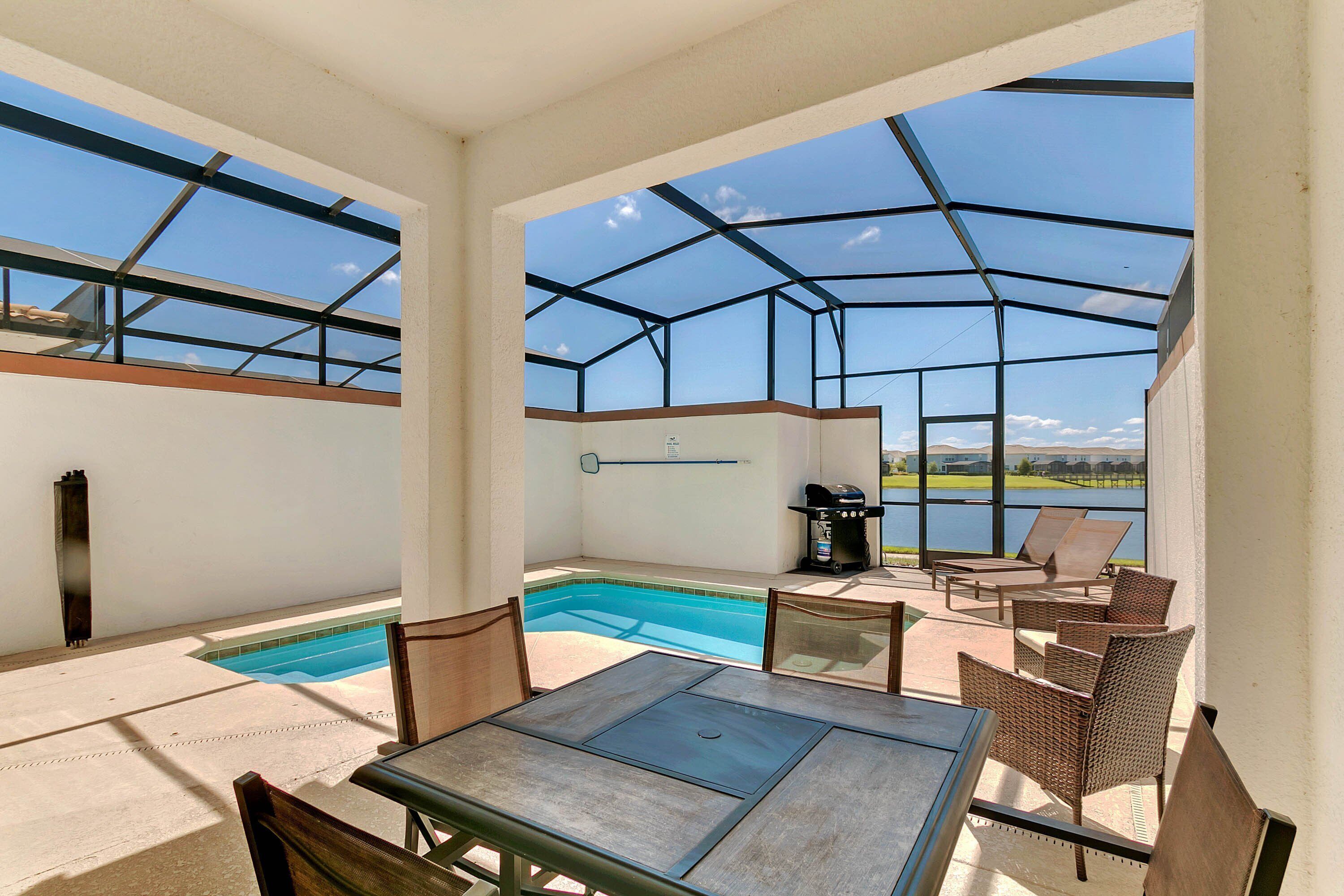 Un espacio exterior techado con piscina, mobiliario y una parrilla.