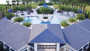 A modern hotel with a central pool, surrounded by palm trees and a lake view. - Last Minute Disney! Private Pool, Hot Tub, Game Room & Themed Bedrooms. Book Now! #65969 (Orlando)