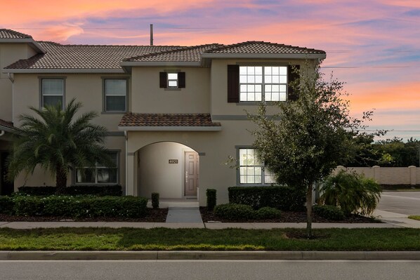 A two-story house with a tiled roof, a front entrance, and a number '4921' on the door.