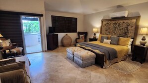 A spacious bedroom with a large bed, a sofa, a chair, and a small table.