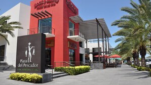Plaza del Pescador with Rock & Brews and a modern building with a red facade.