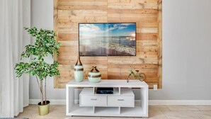 A modern living room with a wooden wall panel, a flat-screen TV, a white entertainment unit, and a potted plant. - Last Minute Disney Getaway! Private Pool & Themed Bedrooms. Book Now! #65997 (Orlando)